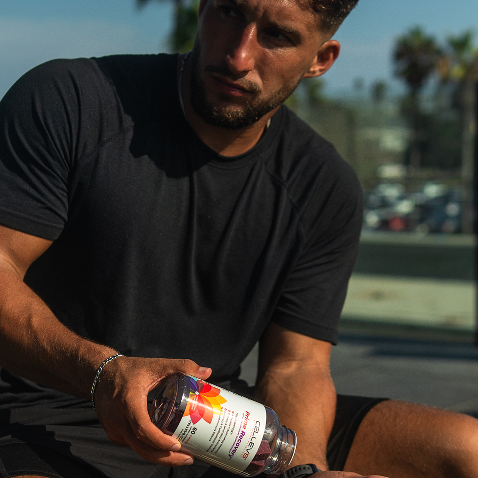 Athlete holding a bottle of Cellev8 Prime Recovery gummies